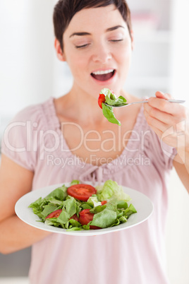 Cheerful woman eating salad