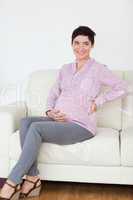 Pretty pregnant woman sitting on a sofa
