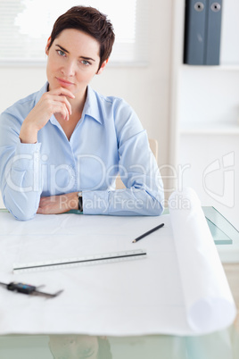 Thoughtful brunette Woman with an architectural plan looking int