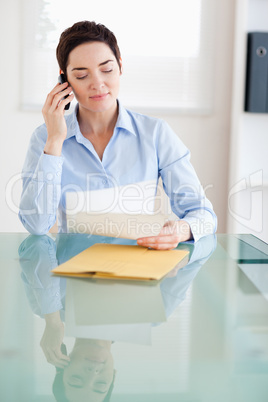 Businesswoman sitting behind a desk with papers on the phone