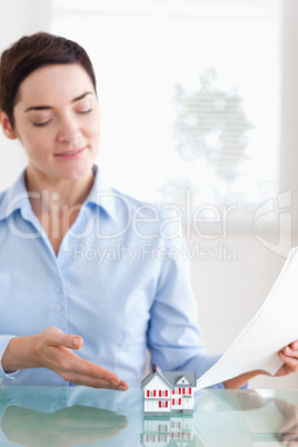 Smiling Woman holding papers showing a model house
