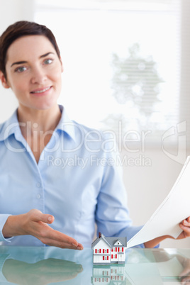 Charming Woman holding papers showing a model house