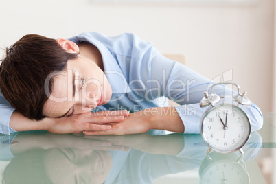 Sleeping cute brunette woman with her head on the desk next to a