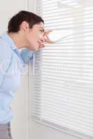 Brunette woman peeking out a window