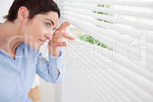 Good-looking brunette woman peeking out a window