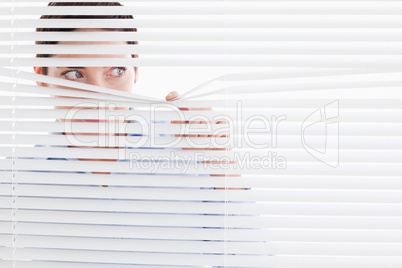 Curious businesswoman peeking out of a window