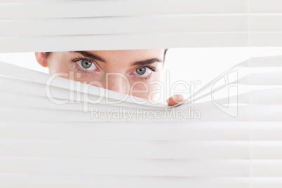 Brunette businesswoman peeking through a venetian blind