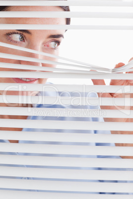 Beautiful businesswoman peeking through a venetian blind