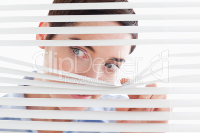 Cute businesswoman peeking through a venetian blind