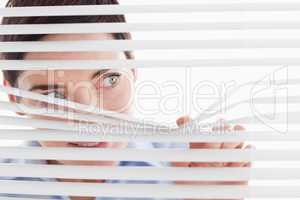 Charming businesswoman peeking through a venetian blind