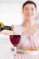 Brunette Woman pouring redwine in a glass