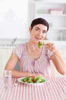 Cheerful brunette woman eating salad