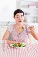 Joyful brunette woman eating salad