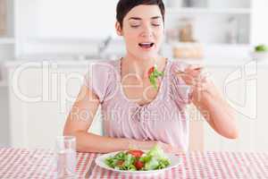 Smiling brunette woman eating salad