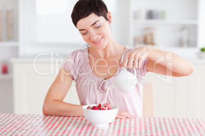 Woman pouring cream over strawberries