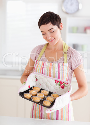 Smiling brunette woman showing muffins