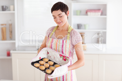 Charming brunette woman showing muffins