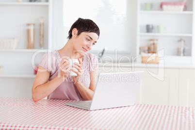 Cute Woman working with a laptop holding a cup
