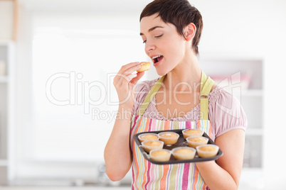 Beautiful brunette woman showing muffins while eating one