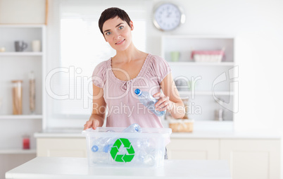 Cute Woman putting bottles in a recycling box