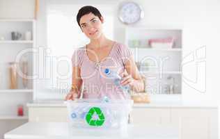 Cute Woman putting bottles in a recycling box