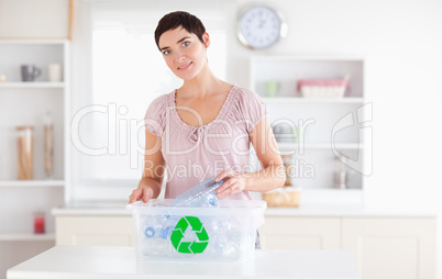 Smiling Woman putting bottles in a recycling box