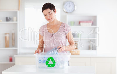 Charming Woman putting bottles in a recycling box
