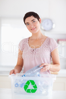Cute brunette Woman putting bottles in a recycling box