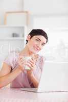Cute woman with a cup and a laptop smiling into the camera