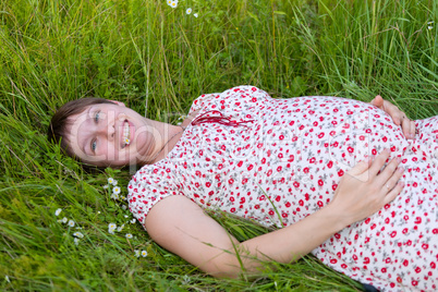 Pregnant woman lie in chamomile