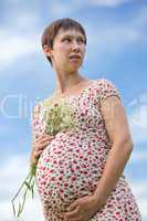 Worried pregnant woman with chamomile bouquet