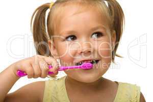 Little girl is cleaning teeth using toothbrush