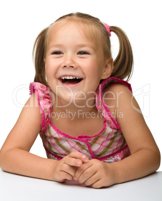 Happy little girl is sitting at the table