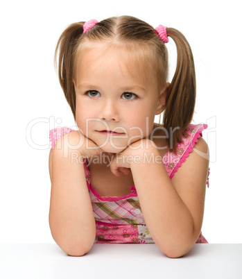 Cute little girl is sitting at the table