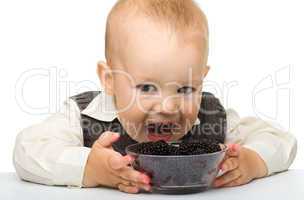 Little boy is eating blackberry