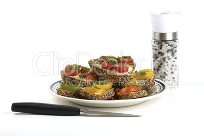 Ein Teller mit Tomaten belegten Vollkornbrot und einer Salz- und Pfeffermühle. A plate of tomato sandwich on wholemeal bread and salt and pepper mill.