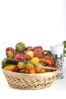 Korb mit frischen Biotomaten, Gemüsemesser und Pfeffer-Salzmühle / Basket of fresh organic tomatoes, vegetable knife and salt and pepper mill