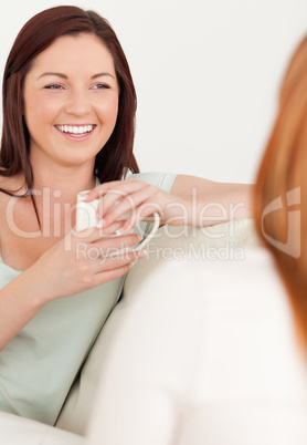 Happy Women sitting on a sofa with cups