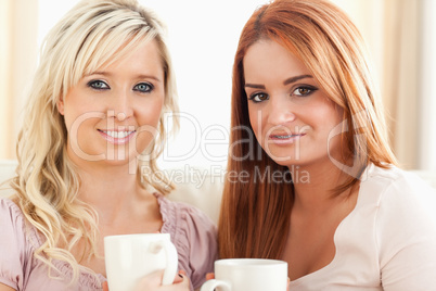 Young Women sitting on a sofa with cups