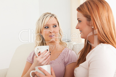 Smiling Young Women sitting on a sofa with cups