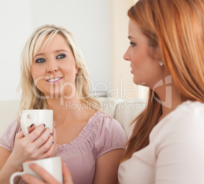 Cute Young Women sitting on a sofa with cups