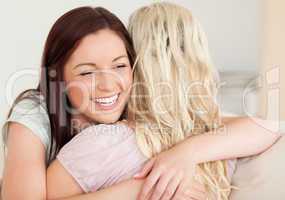 Joyful women hugging on a sofa