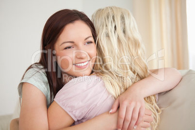 Young women hugging on a sofa