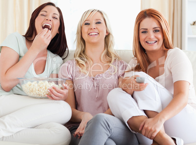 Laughing Friends lounging on a sofa watching a movie