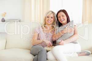 Joyful women lounging on a sofa watching a movie