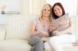 Gorgeous young women lounging on a sofa watching a movie