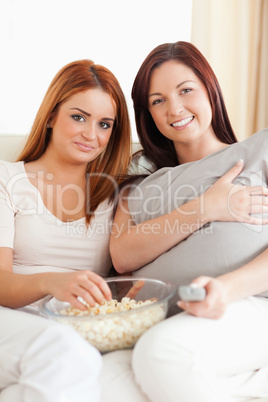 Smiling young women lounging on a sofa watching a movie