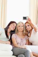 Young women lounging on a sofa with a camera