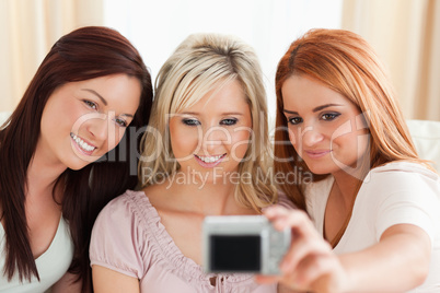 Smiling women lounging on a sofa with a camera
