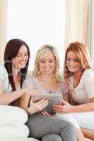 Smiling women lounging on a sofa with a tablet